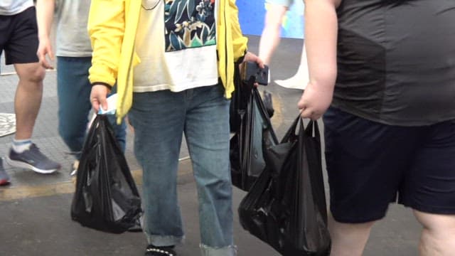 People walking around the market carrying plastic bags