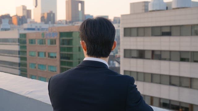 Man in a suit looking at buildings from a rooftop