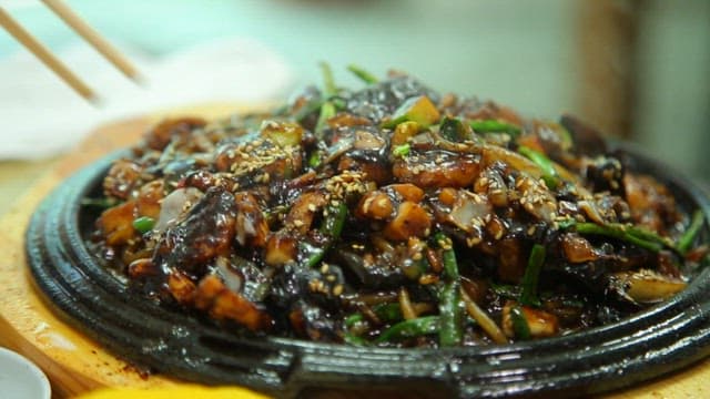 Seafood Jjajang noodles on an iron plate with steaming hot sauce