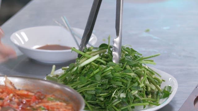 Fresh water parsley going into a boiling hot pot in a pot