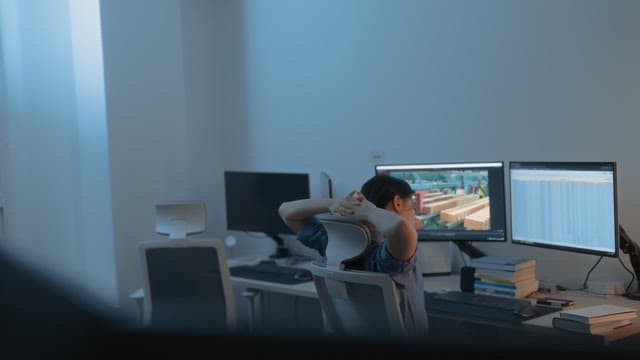 Person working at a desk with dual monitors