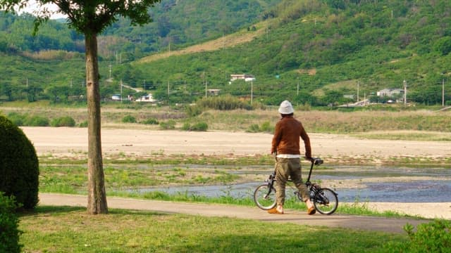 Man walking his bike on a iverside path
