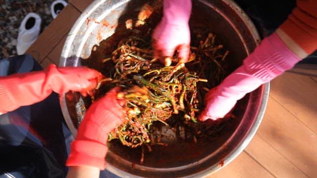 Preparing kimchi with fresh green onions in a metal basin