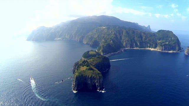 Serene Island Coastline with Passing Boats