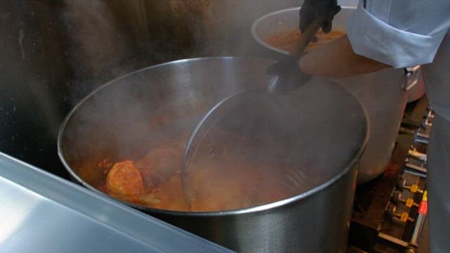 Pig's feet being boiled in a large steaming pot