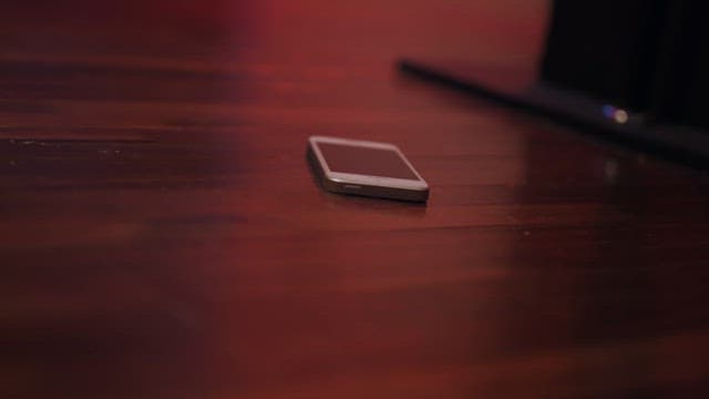 Smart phone lying on an indoor dark wooden floor