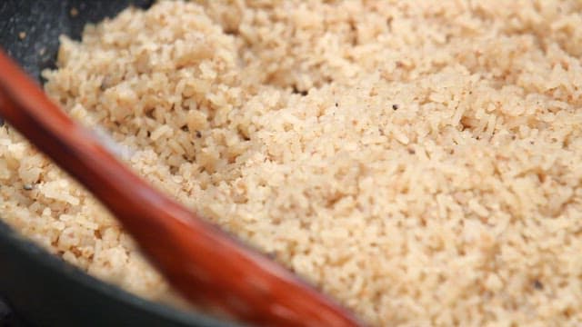 Stirring minced meat and noodles in a pan with a wooden spatula