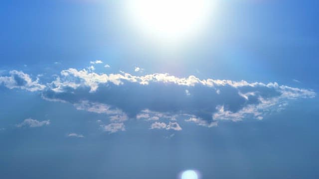 Bright sun shining over fluffy clouds