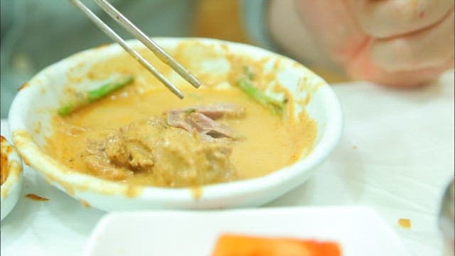 Picking up duck meat in a plate with chopsticks