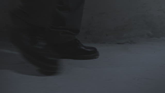 Feet of a person walking on concrete floor
