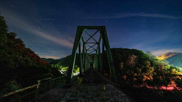 Night sky visible over the mountains and bridge