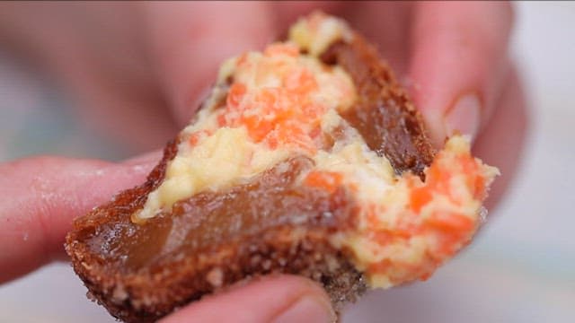 Hands holding a carrot-made glutinous rice donut