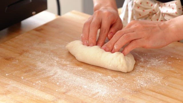 Woman shaping dough on a wooden board
