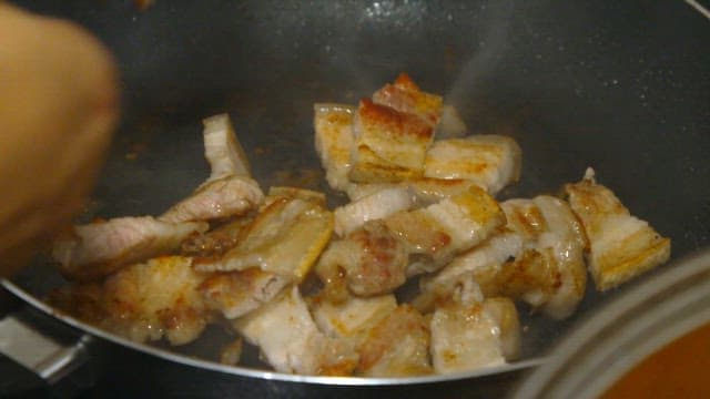 Pork belly sizzling in a hot pan