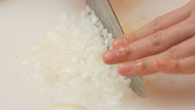 Chopping onions on a white cutting board with knife