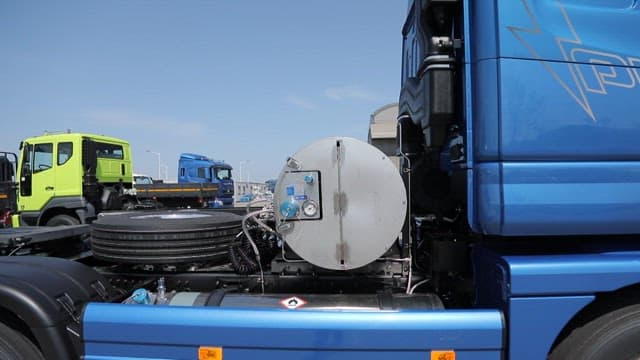 LNG trucks parked near a storage facility under clear skies