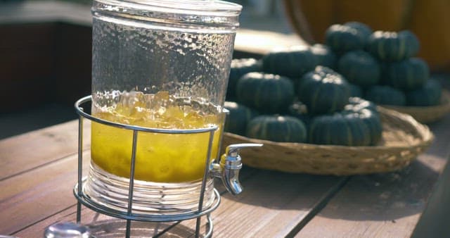 Dispenser with Lemonade and Pumpkins on a Wooden Bench