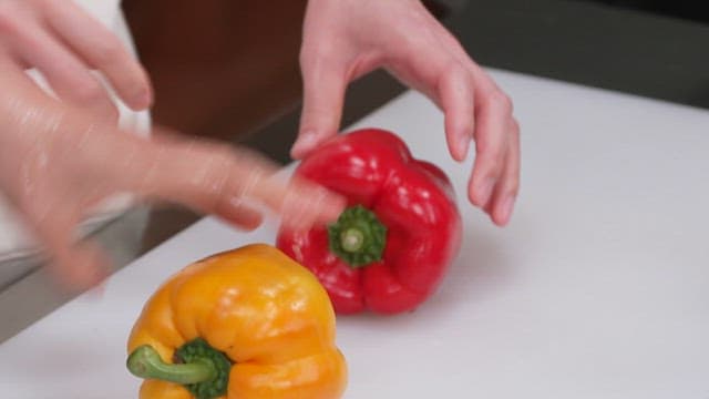 A person cutting bell peppers on a kitchen counter