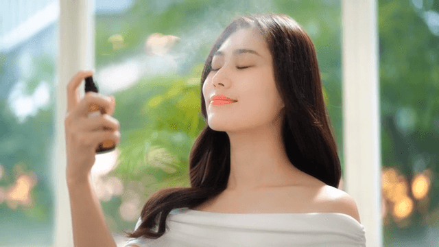 Woman sprays facial mist in a bright room