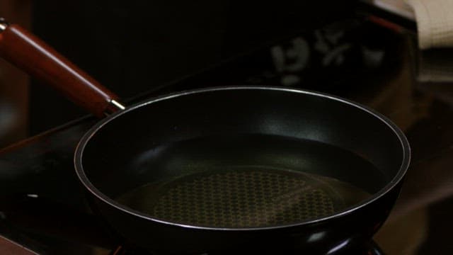 Putting battered meat to boiling oil in a frying pan
