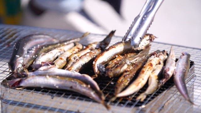 Grilling the sand eels until golden brown on the barbecue grill
