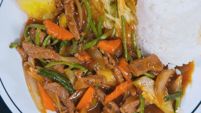 A plate of rice with stir-fried beef and vegetables