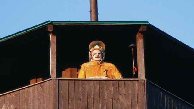 Firefighter mannequin in a wooden balcony on a sunny day