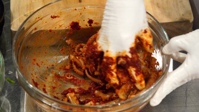 Mixing spicy seasoning and octopus in a glass bowl