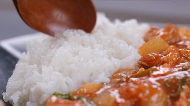 Rice bowl with stir-fried radish and pork mixed with a spoon