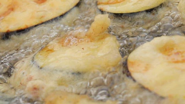 Slices of eggplant frying in hot oil