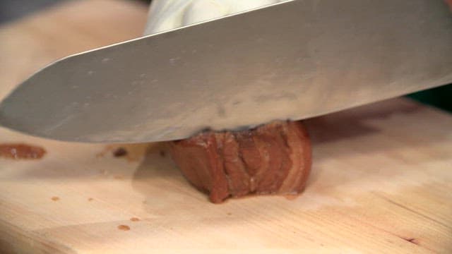 Slicing boiled pork slices on a wooden cutting board