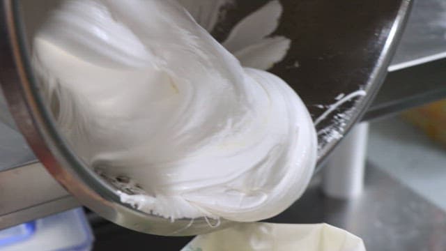 White Cream Being Poured into a Container in a Food Factory