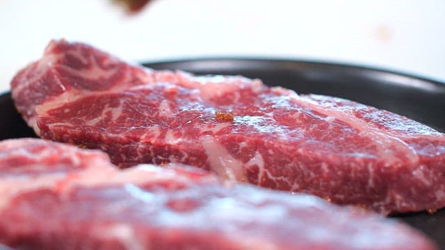 Applying seasoning to fresh steak beef
