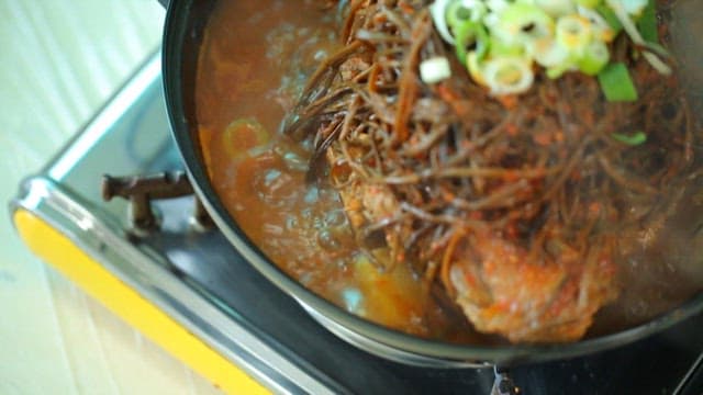 Plate of pork backbone stew topped with sweet potato stem salad
