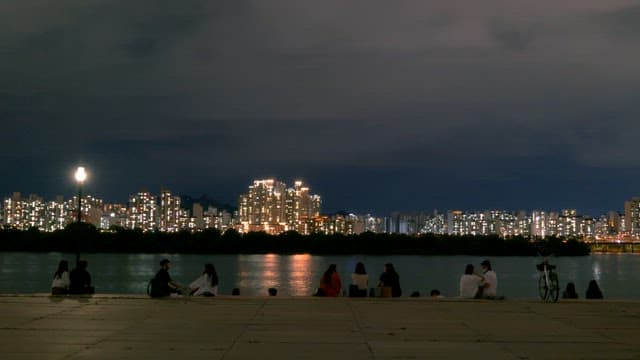 People sitting on the riverside and enjoying the night view