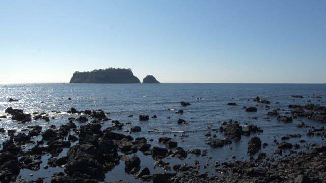 Island in the distance on a rocky ocean shore of Jeju Island