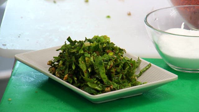 Seasoned spinach salad being prepared on a plate