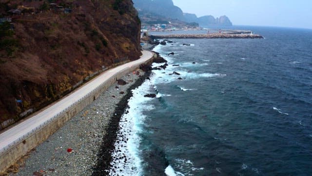 Coastal road winding alongside the ocean and mountains.
