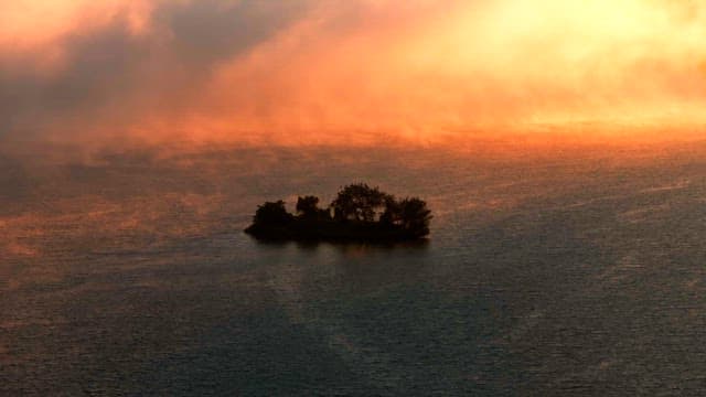 Small island surrounded by mist at sunset