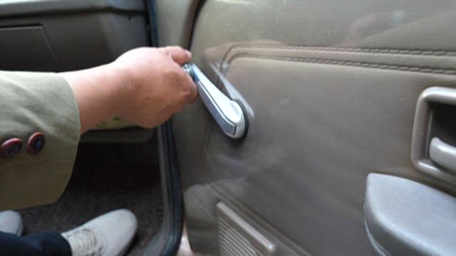 Person opening a window by turning a handle in a car