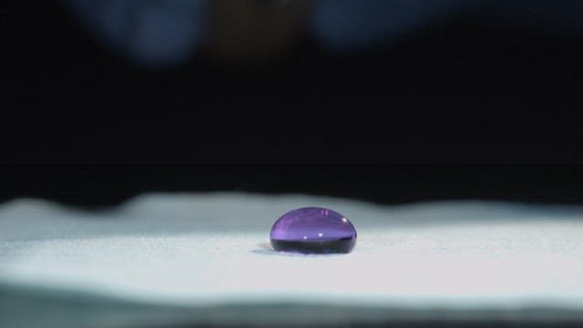 Purple liquid being delicately sliced in half by a knife