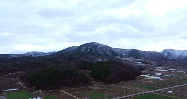 Village with farmland and houses under snowy mountains
