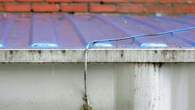Raindrop falling on corrugated metal roof with rust of conatiner building