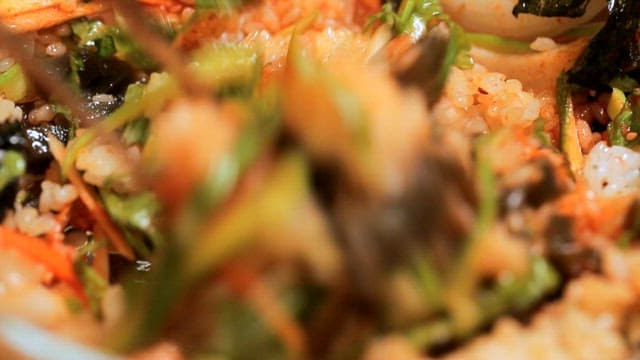 Korean bibimbap being mixed with vegetables