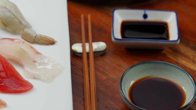 A plate of assorted sushi with soy sauce on a wooden table