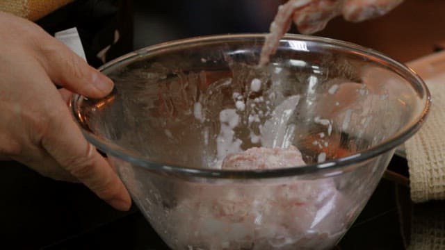 Putting battered meat to boiling oil in a frying pan