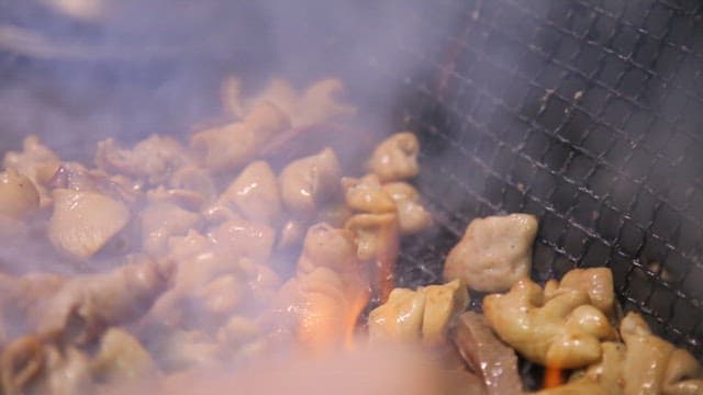 Pork intestines sizzling on a grill over charcoal