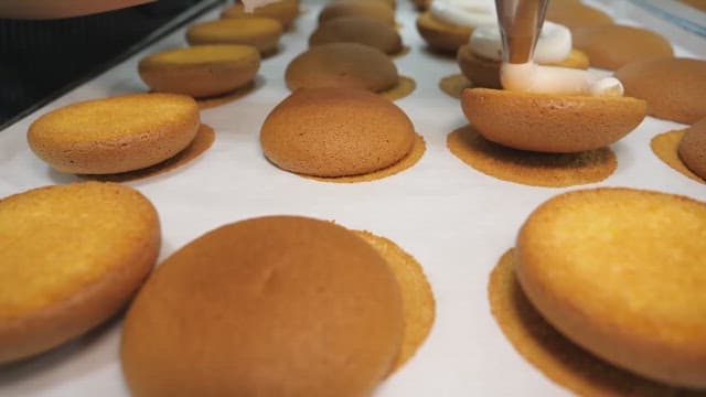 Piping cream onto freshly baked cookies in a bakery