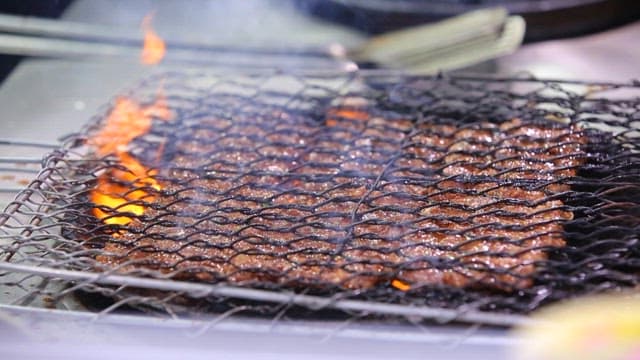 Grilling tteokgalbi on a grill over charcoal
