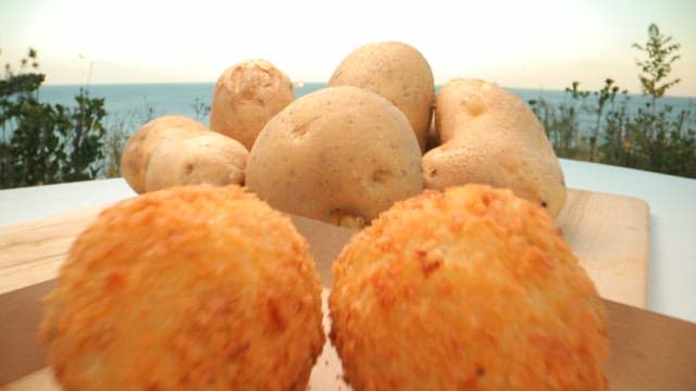 Crispy potato croquettes, ketchup and fresh potato plated on a table by the sea